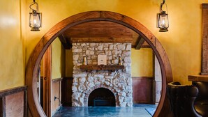 A stone fireplace with a wooden archway, two lanterns, and a leather chair. - Hobbit House in Cliffview Resort, Artisan Crafted, Themed. Centrally Located (Campton)