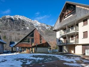 Un bâtiment moderne doté d’un toit en pente, de grandes fenêtres et offrant une vue sur des montagnes enneigées.