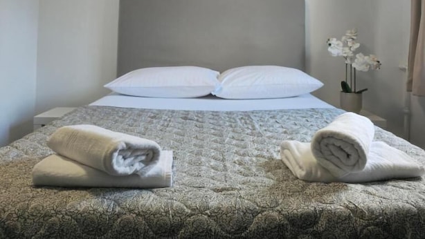 Un lit bien fait, recouvert d’une couvre-lit à motifs, avec deux oreillers et des serviettes enroulées posées sur le côté. Trois œuvres d’art encadrées sont accrochées au mur, au-dessus du lit.