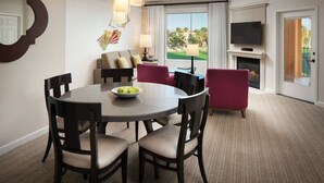 A hotel room with a dining area, a sofa, a TV, and a fireplace. - 2 Bedroom Villa @ SHADOW RIDGE - Rest and rejuvenate from Stage Coach (Palm Desert)