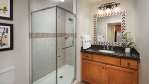 A bathroom with a glass-enclosed shower, a sink with a mirror, and wooden cabinets. - 2 Bedroom Villa @ SHADOW RIDGE - Rest and rejuvenate from Stage Coach (Palm Desert)