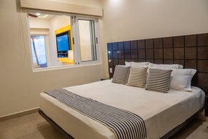 Une chambre d’hôtel avec un grand lit, une tête de lit, une fenêtre et une vue sur la mer.