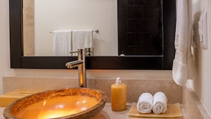 A bathroom with a stone sink, a mirror, a towel rack, and a soap dispenser. - Two Bedroom Ocean Front (Bajos de Chila)