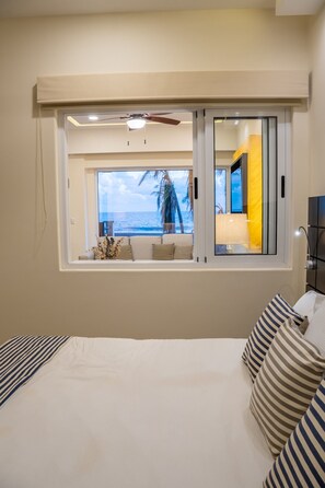 Ein Schlafzimmer mit einem großen Bett, einem Fenster mit Meerblick und einem Deckenventilator.