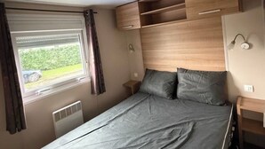 A compact bedroom with a single bed, built-in wooden storage, a window with curtains, and a radiator. - A splendid place les mathes la Palmyre la rochelle .royan lieux plage dynamic (Les Mathes)