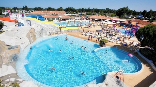 A large outdoor swimming pool with multiple lanes, surrounded by beach chairs and umbrellas, and a rocky landscape. - A splendid place les mathes la Palmyre la rochelle .royan lieux plage dynamic (Les Mathes)