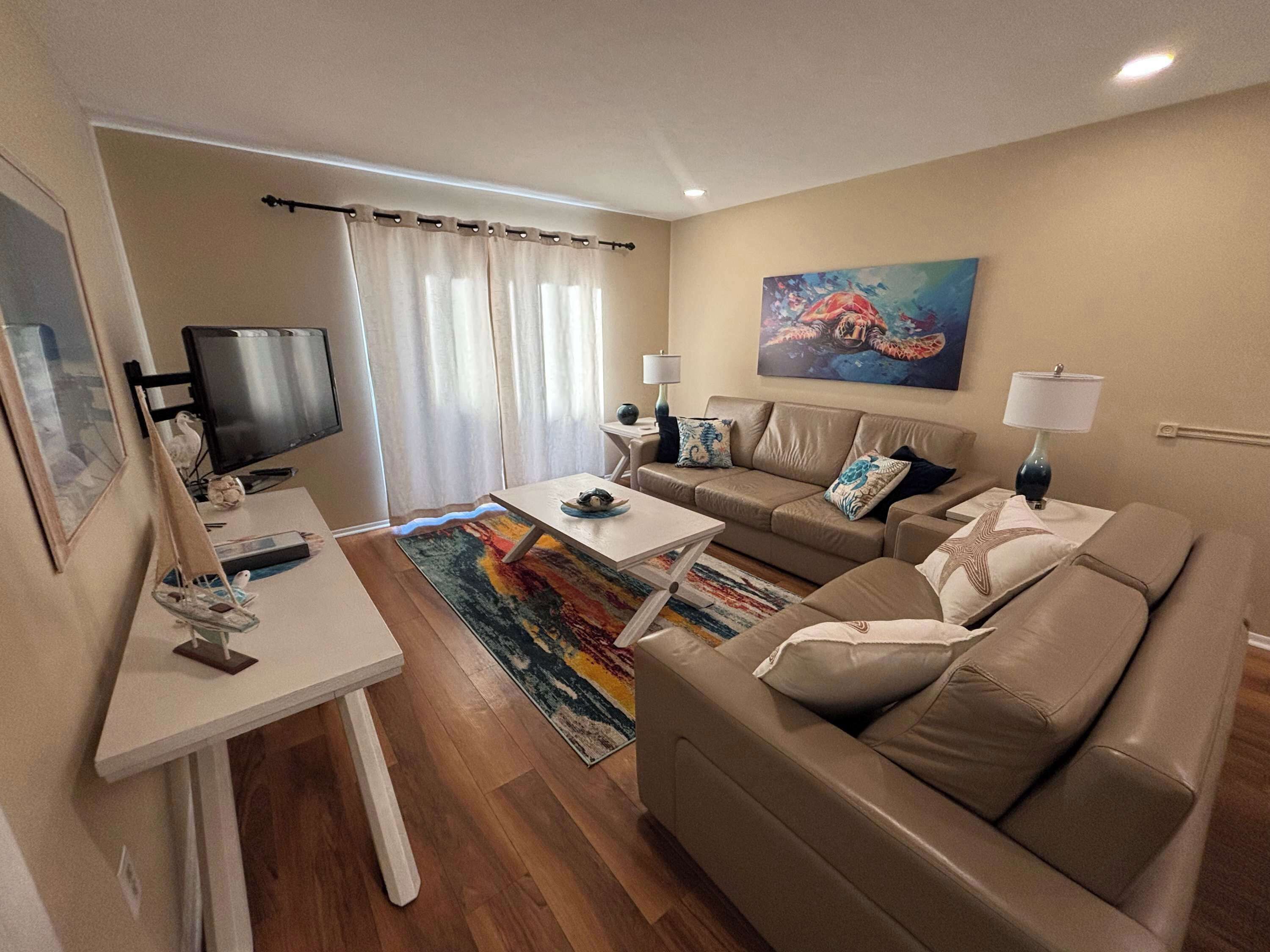 A living room with a sofa, a coffee table, a TV, and a painting on the wall.