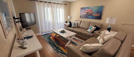 A living room with a sofa, a coffee table, a TV, and a painting on the wall.