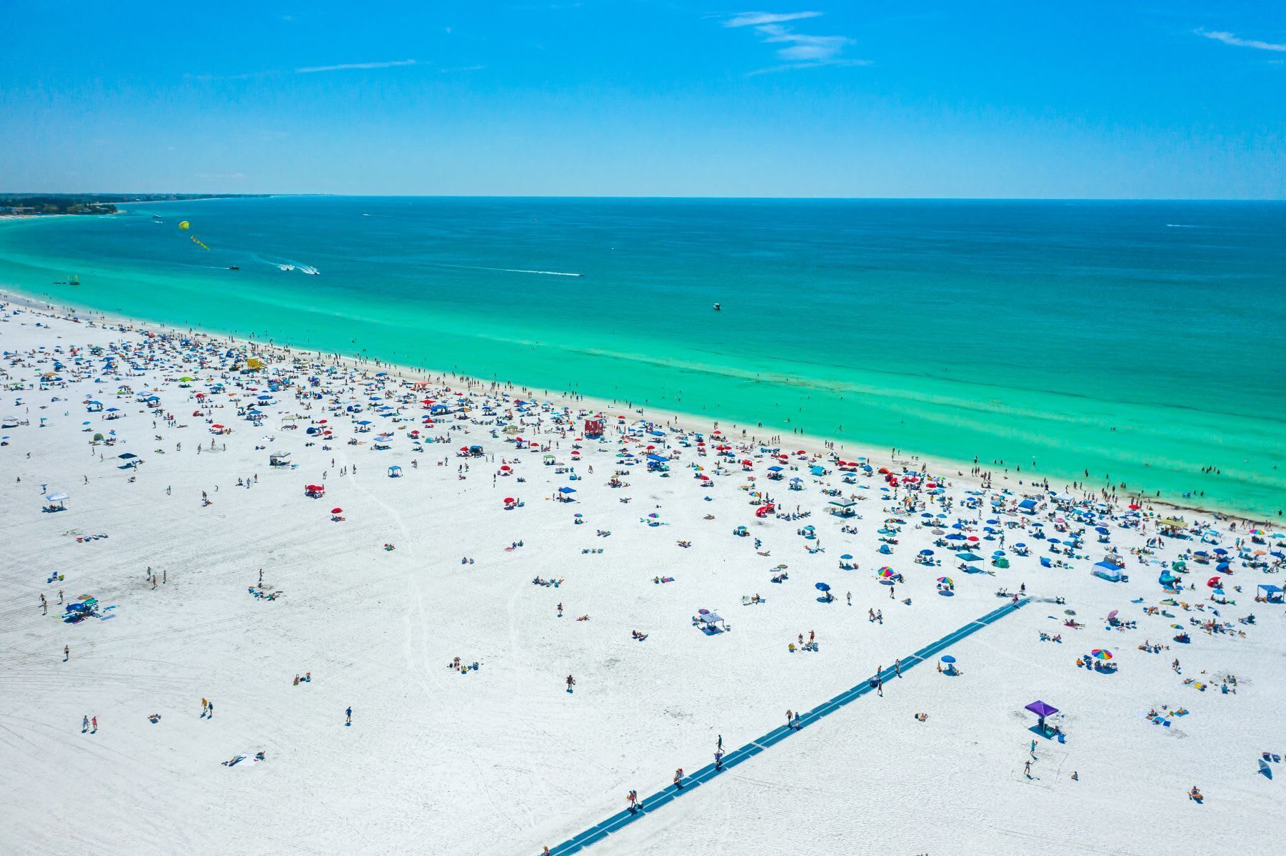 A beach with numerous umbrellas and people.