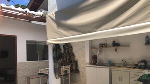 Une cuisine équipée d’une cuisinière intégrée, d’un évier et d’un plan de travail. On y trouve une fenêtre et une porte qui donne sur une autre pièce.