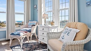 A room with a wicker chair, a white dresser, and a view of the ocean. - Spring Discount! 300ft to Beach+Heated Pool/Multiple Decks with Ocean Views (Emerald Isle)