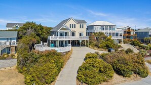 A coastal residential area with multiple two-story houses featuring balconies, a central walkway, and surrounding greenery. - Spring Discount! 300ft to Beach+Heated Pool/Multiple Decks with Ocean Views (Emerald Isle)