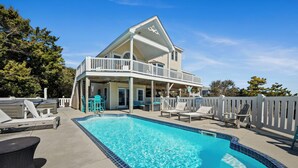 A two-story house with a swimming pool, deck chairs, and a white fence. - Spring Discount! 300ft to Beach+Heated Pool/Multiple Decks with Ocean Views (Emerald Isle)
