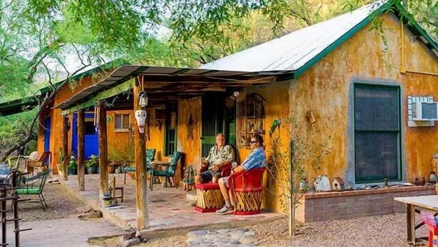 Una casa de madera rústica con un porche, un sendero de piedra y un pequeño jardín.