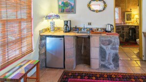 Una cocina compacta con refrigerador integrado, un lavamanos y una cafetera.