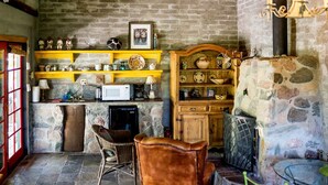 Un'atmosfera rustica con pareti in pietra, scaffali in legno, un camino e un'area pranzo con sedie e tavolo.