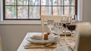 A dining table set with plates, glasses, and cutlery. - Sebago Pines Hideaway-Fire Pit/Beach Access/Family Friendly (Naples)