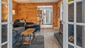 A cozy living room with a sofa, a coffee table, and a fireplace. - Sebago Pines Hideaway-Fire Pit/Beach Access/Family Friendly (Naples)