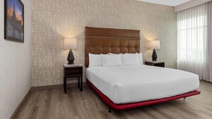 A hotel room with a large bed, two bedside tables with lamps, a patterned wall, and a framed picture on the wall. - Drury Plaza Hotel Mobile (Mobile)