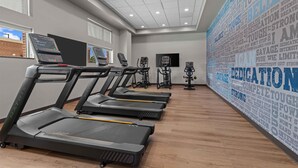 Un gimnasio con cintas de correr, bicicletas estáticas y una pared con mensajes motivacionales.