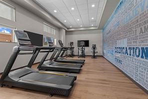 Un gimnasio con cintas de correr, bicicletas estáticas y una pared con mensajes motivacionales.
