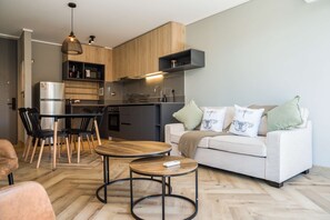 A modern kitchen with wooden cabinets, a built-in oven, and a dining area with a round table and chairs. - Stylish Urban Oasis Spacious 1BR in Providencia (Providencia)