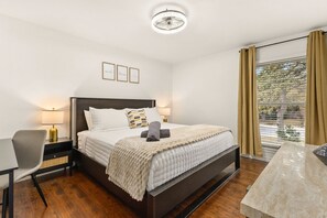 A hotel room with a bed, bedside tables, a chair, a desk, and a window with curtains. - Modern Family Retreat - Private Pool/Mini Golf/Fire Pit/Pool Table - Sleeps 14 (San Antonio)