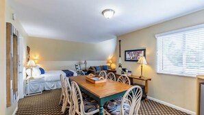 A cozy room with a bed, a sofa, a dining table with chairs, and a window with blinds. - Top Floor Chalet that sleeps large groups (Whitehall)