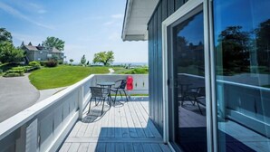 Een balkon met een tafel en stoelen, met uitzicht op een gazon en een gebouw.
