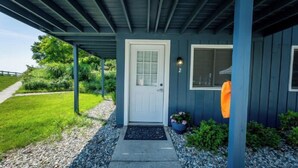 A house with a white door, a small porch, and a garden area with gravel and plants.