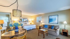A hotel room with a bed, a sofa, a dining table, and a chandelier. - Lakefront king studio with queen sofa sleeper  (Whitehall)