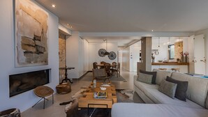 Ein modernes Wohnzimmer mit Kamin, Essbereich und einer Küche im Hintergrund.