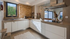 Eine moderne Küche mit weißen Schränken, einem großen Fenster und einer Wand mit Steinverkleidung.