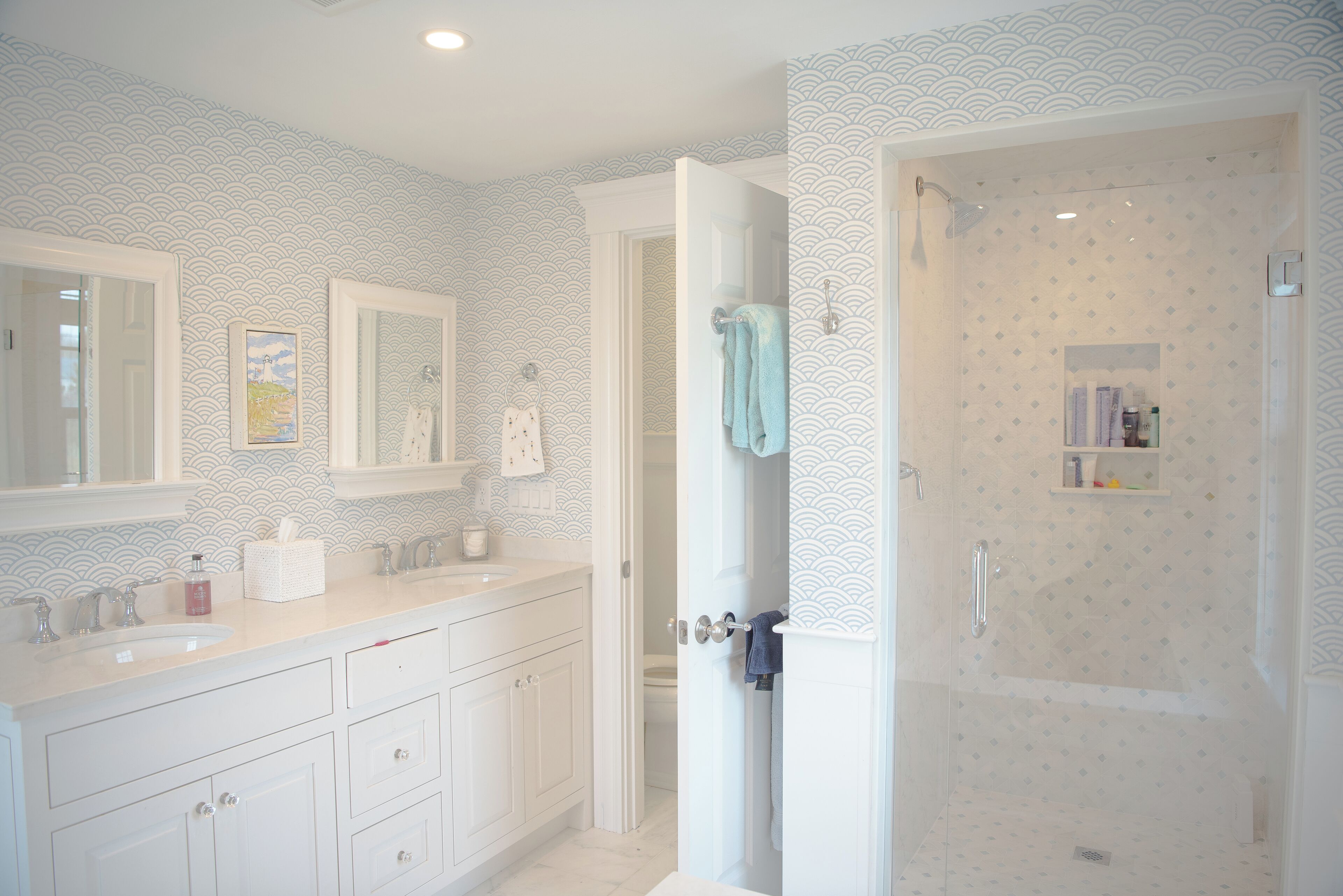 A bathroom with a white vanity, a shower, and a toilet.