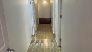 Un pasillo estrecho con piso de madera y paredes blancas.