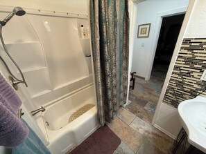 A bathroom with a bathtub, shower, and a sink.