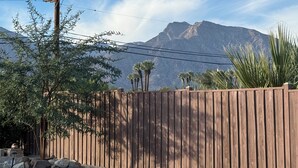 Une clôture en bois, un sol rocailleux, un poteau électrique et une montagne en arrière-plan.