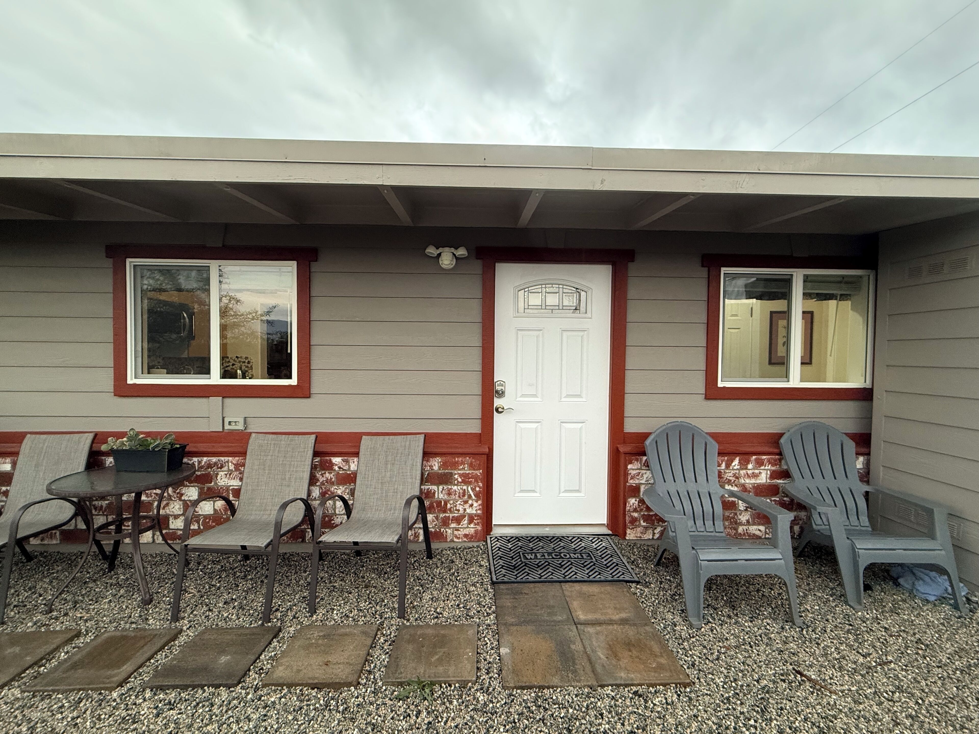 Una casa amb un porxo, dues finestres, una porta i tres cadires Adirondack.