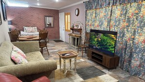 Un salon avec un canapé, un fauteuil en cuir rouge, un téléviseur et un rideau à motifs.