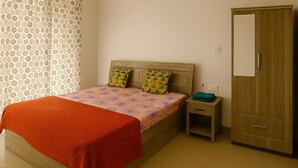 Ein Schlafzimmer mit einem Bett, einem Nachttisch, einem Kleiderschrank und einem gemusterten Vorhang.