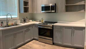 Una cocina moderna con armarios grises, un microondas de acero inoxidable, una estufa a gas y un horno integrado.