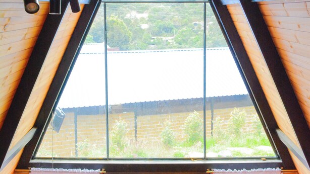 A triangular wooden ceiling with a large window. - El Encanto de Ráquira Lodge (raquira)