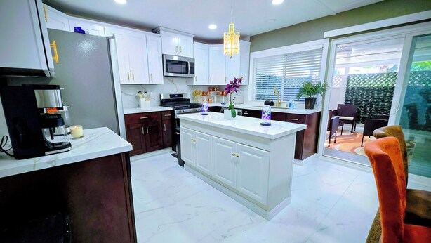 Una cocina moderna con gabinetes blancos, una isla central, un microondas y una cafetera.