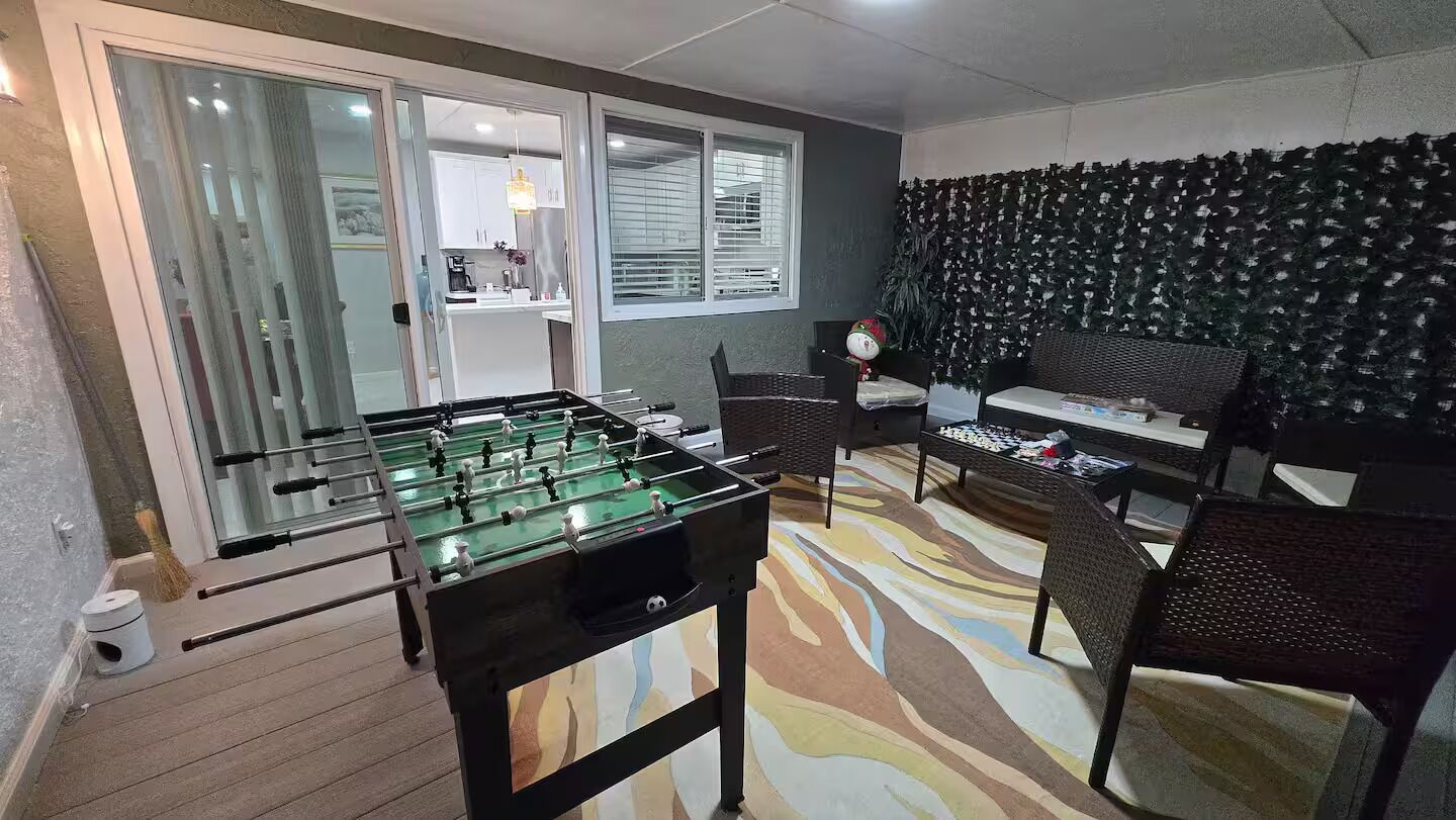 A room with a foosball table, a sofa, and a patterned carpet.