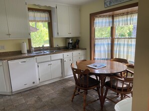 A kitchen with white cabinets, a dishwasher, a coffee maker, and a dining table with chairs. - Cedarwood, Rent 3 Get one Free Nov. 1 - May 31st! - Fish Creek, Family Friendly (Fish Creek)