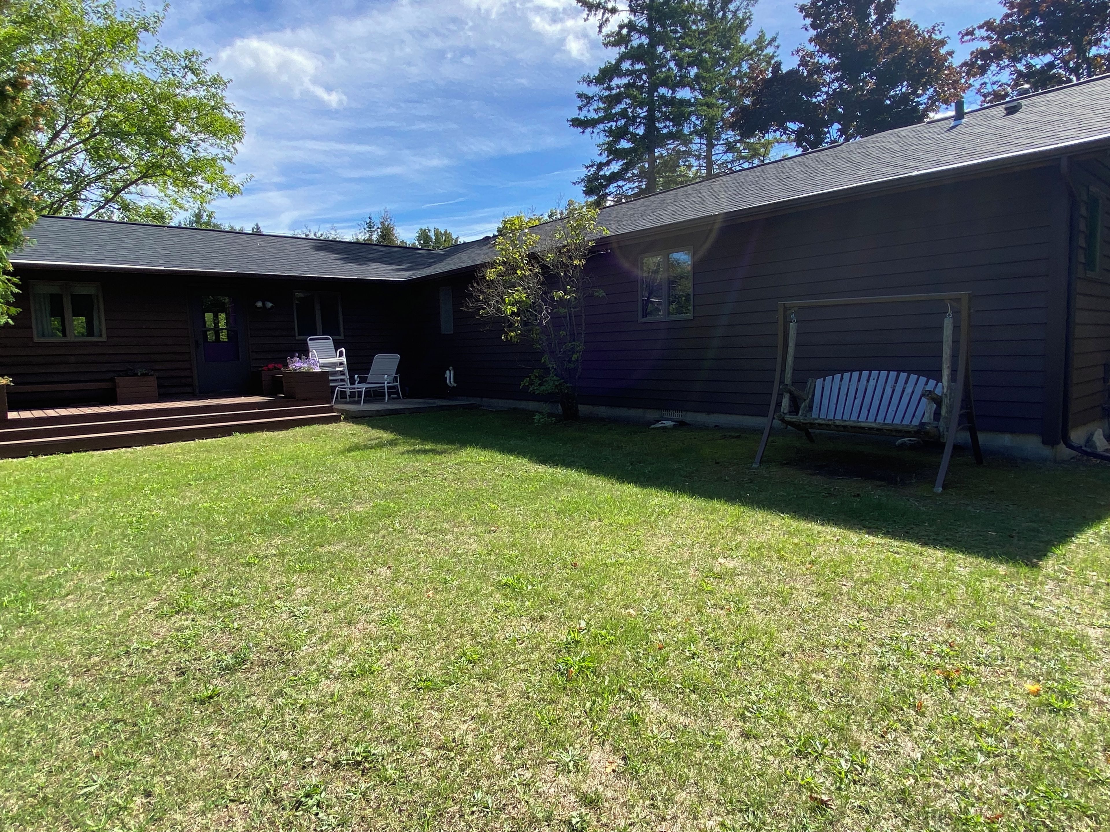 A wooden house with a covered porch, a lawn, and a swing set.