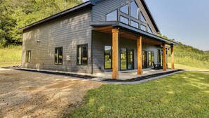 A modern two-story house with a covered porch and large windows. - Discover the perfect escape in our brand-new, secluded cabin in nature's embrace (Blue River)