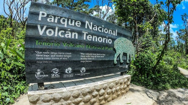En skylt för nationalparken Volcán Tenorio, med citat av Jorge Debravo och logotyper från olika organisationer.