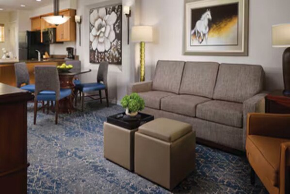 Een moderne hotelkamer met een bank, voetenbankje en een zithoek met stoelen en een tafel.