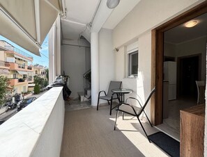 A balcony with a view of neighboring buildings, a small table and chairs, and a door leading to the interior. - Elegant and Cozy Escape in Nikopoli Thessaloniki (Pavlos Melas)